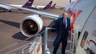 Photo of Fred Smith standing on airstairs next to a fedex plane on a tarmac